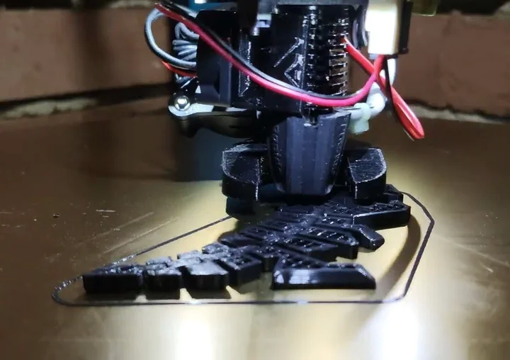 Close-up of the modified Predator printhead printing a black part on its circular bed.